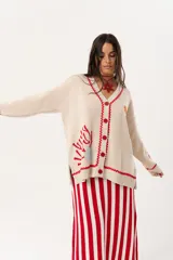 Saco oversize tejido con ilustraciones inspiradas en corales, peces, estrellas de mar y tortugas. Presenta galón picot en rojo en cartera y puños, y botones a tono.