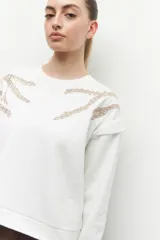 Buzo de manga larga color blanco, con cuello redondo y detalles de bordado orgánico.