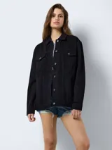 Chaqueta de jean negra de corte oversize, con cuello clásico, cierre frontal con botones metálicos, bolsillos delanteros con solapa y botón, y mangas largas.