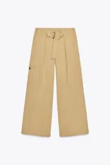 Pantalón color beige de tiro alto con cinturón ajustable con hebilla metálica. Presenta bolsillos laterales, de vivo en la pierna y de parche en la espalda.
