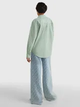 Camisa de corte amplio, a rayas verticales verdes y blancas, con cuello inglés, cierre frontal con botones y logo de Tommy Hilfiger bordado en el puño.