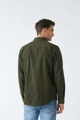 Camisa de pana color verde militar, de corte regular, con cuello clásico y cierre frontal con botones.