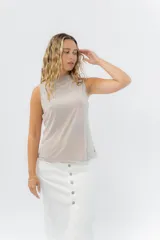 Musculosa color rosa metalizado, sin mangas, confeccionada en lino metalizado, con escote cerrado al frente y espalda abierta con lazo ajustable.