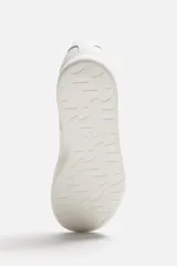 Zapatillas urbanas de cuero liso color blanco, con cordones y suela plana.