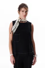 Top sin mangas color terracota con cuello redondo y bolsillo frontal. Presenta costuras a contratono en blanco que definen los bordes y el bolsillo.