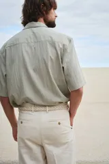 Camisa color verde claro con cuello inglés, tapeta lisa y canesú en la espalda. Modelo de manga corta con dos bolsillos superiores abiertos y bajo recto con aberturas laterales.