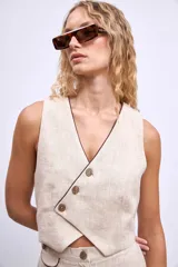 Chaleco color crudo con cuello en V y botones frontales.