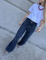 Pantalón jean azul oscuro, de corte wide leg y tiro medio. Presenta detalles de costuras diagonales en la parte superior.