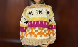 Sweater de lana merino con cuello redondo y diseño con motivos geométricos en tonos azul, marrón, naranja, verde y beige.