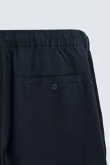 Pantalón azul marino de corte recto, confeccionado en tejido de algodón y lino. Tiene cintura elástica ajustable con cordón, bolsillos delanteros y traseros de vivo.
