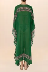 Kaftán largo verde oscuro con patrón geométrico en rosa y blanco, semi-traslúcido, con mangas amplias y escote en V con aplique central.