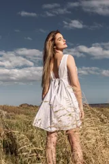 Vestido corto blanco con escote en V y lazo ajustable en el centro del busto.