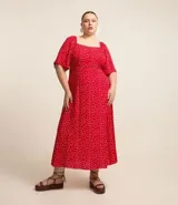 Vestido midi rojo con estampado de lunares blancos, escote cuadrado, mangas cortas con volados y falda acampanada. Presenta detalle de lastex en la espalda y abertura frontal. Confeccionado en viscosa.