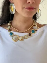 Collar dorado con eslabones grandes y piedras de colores: azul, marrón, blanco y crema.