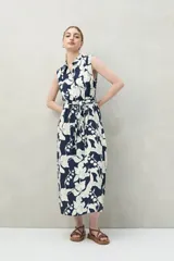 Vestido midi camisero sin mangas, con estampado floral blanco sobre fondo azul marino y lazo en la cintura.