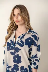 Camisa larga de color blanco con estampado de flores azules, cuello en V y mangas largas.