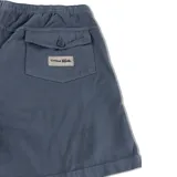 Bermuda de lona color azul oscuro con cintura elástica y cordón de ajuste color crema. Presenta paneles con costuras visibles y un pequeño parche de tela con el logo "Critical Slide" en la parte inferior del muslo derecho.