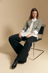 Cárdigan de tejido de punto a rayas horizontales anchas, color crema y negro. Presenta un cuello tipo chal que se anuda al frente como un lazo.