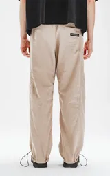 Pantalón beige de corte sastrero con bolsillos laterales, estilo holgado y tela suede. Cintura trasera con doble ajuste elástico y tanca, cintura delantera con botón y cierre.