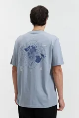 Remera celeste de manga corta con estampado de mapa mundial en azul en la espalda y logo triangular en el frente.