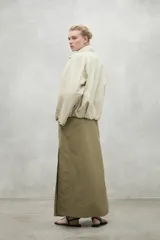 Campera color crema de corte oversize con capucha ajustable, cierre frontal con botones a presión y bolsillos laterales con solapa. Fabricada con poliamida reciclada, impermeable y transpirable.