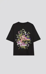 Remera negra oversize de algodón con estampado en la espalda de moléculas y hojas de marihuana en tonos rosa, amarillo y verde.