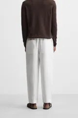 Pantalón de lino color marrón oscuro, de corte recto y relaxed fit. Tiene cintura elástica ajustable con cordón, bolsillos frontales y traseros de parche.