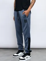 Pantalón de jogging gris claro con recortes laterales en gris oscuro, logo de Umbro estampado en el muslo y cintura ajustable con cordón. Confeccionado en tejido french terry de poliéster.