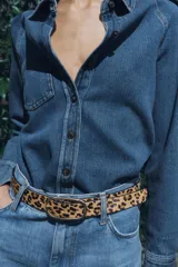 Cinturón de cuero con estampado animal print y hebilla ovalada dorada.