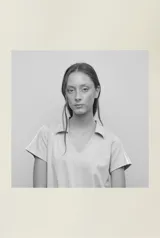 Camiseta confeccionada en remería de algodón, color beige, con cuello tipo polo y escote en V. Presenta dos líneas aplicadas en los laterales de cada manga.