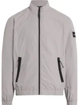 Campera Calvin Klein color gris claro, confeccionada en nailon arrugado reciclado, con cuello alto, puños y bajo elásticos, cierre frontal con cremallera, bolsillos laterales con cremallera, abertura de ventilación en la espalda, forro de poliéster reciclado e insignia con el logo de goma en la manga.