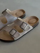 Sandalias de verano color beige con doble tira y hebillas plateadas.