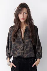 Camisa marrón con estampado abstracto en tonos cobre y negro, cuello mao y mangas largas abullonadas con puños elásticos.