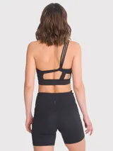 Top deportivo negro de un hombro con tirantes triples elásticados en la espalda, almohadillas removibles y calce regular.