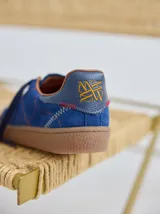 Championes urbanos de cuero color beige con pespuntes laterales en verde y azul. Suela de goma color caramelo.