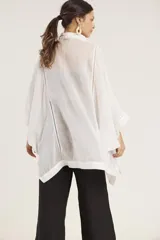 Camisa blanca de lino con corte amplio, cuello camisero y mangas 3/4 con detalle de puntilla en el borde.