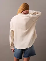 Camisa color crema de gasa doble, con cuello de punta, bolsillo de parche en el pecho, mangas largas con cierre de solapa enrollable y corte regular.