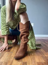 Botas de cuero color marrón, de caña alta y estilo cowboy.