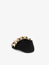 Zapato plano negro de tela con punta fina y aplique metálico dorado en el empeine.
