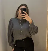 Camisa gris de muselina de algodón con cuello mao, mangas largas abullonadas con puños elásticos y cierre frontal parcial con botones de nácar.