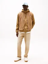 Chaleco de lona color marrón claro con capucha, cierre frontal con cremallera, dos bolsillos delanteros ribeteados, un bolsillo interior y parche con logo de Tommy Jeans en el pecho.