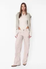 Body manga larga color beige, de punto roma, con cuello medio alto con cierre de nylon a tono. Tiene recortes pisados con bordador, mangas ranglan con mitones en los puños, broches snap en la entrepierna y elástico interno en el contorno de tiro.