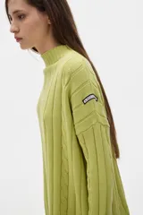 Sweater tejido color borgoña con cuello alto, corte oversize y mangas largas con detalle de trenzas verticales.