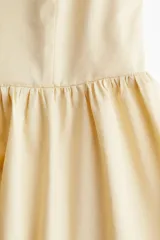 Vestido corto color crema, de algodón, con breteles finos, escote corazón, cuerpo entallado, espalda fruncida y falda con vuelo.