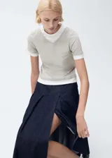 Remera color gris claro con cuello en V y mangas cortas. Diseño de doble capa con remera blanca debajo.