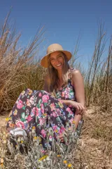 Vestido largo negro con estampado floral multicolor, escote en V, breteles finos y volados en el cuello.