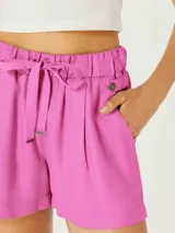 Short femenino color fucsia, de tiro alto con cintura elástica fruncida y lazo ajustable a tono. Presenta pliegues frontales y bolsillos laterales.