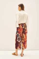Pantalón capri con estampado floral en tonos naranja, rojo, azul y marrón. Tiene corte regular, bolsillos laterales y elástico en la parte trasera de la cintura.