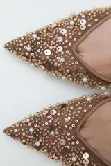 Zapato destalonado color beige con puntera fina, confeccionado en mesh con abalorios y tira trasera elástica. Tacón fino de 8 cm.