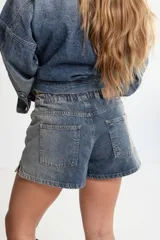 Short de jean azul con cintura elástica y cordón blanco con letras rojas.